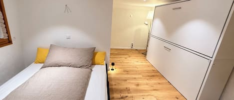 A bedroom with a bed, a wardrobe, and a bedside table.