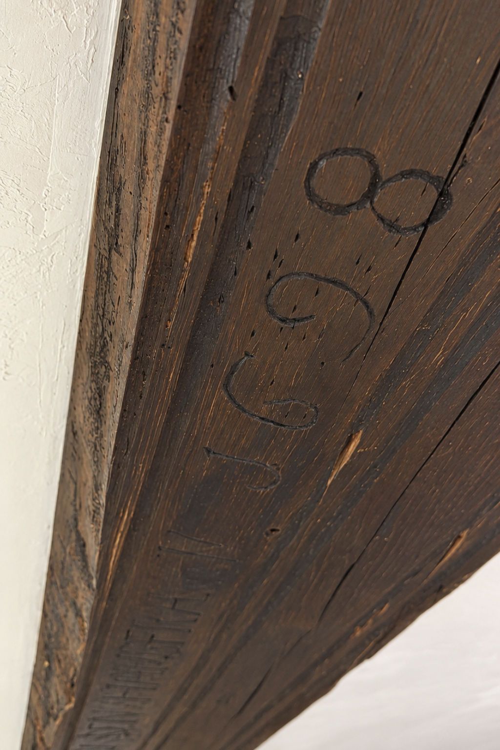 A close-up of a wooden beam with a dark stain and a circular mark.