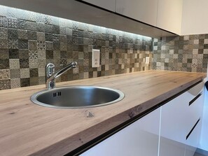 A kitchen with a modern stainless steel sink, wooden countertop, and decorative mosaic backsplash. - Ilse EG Süd-West Appartement/Fewo, Dusche oder Bad, WC 3 Zimmerwohnung, 3-Betten by Interhome (Fiesch)