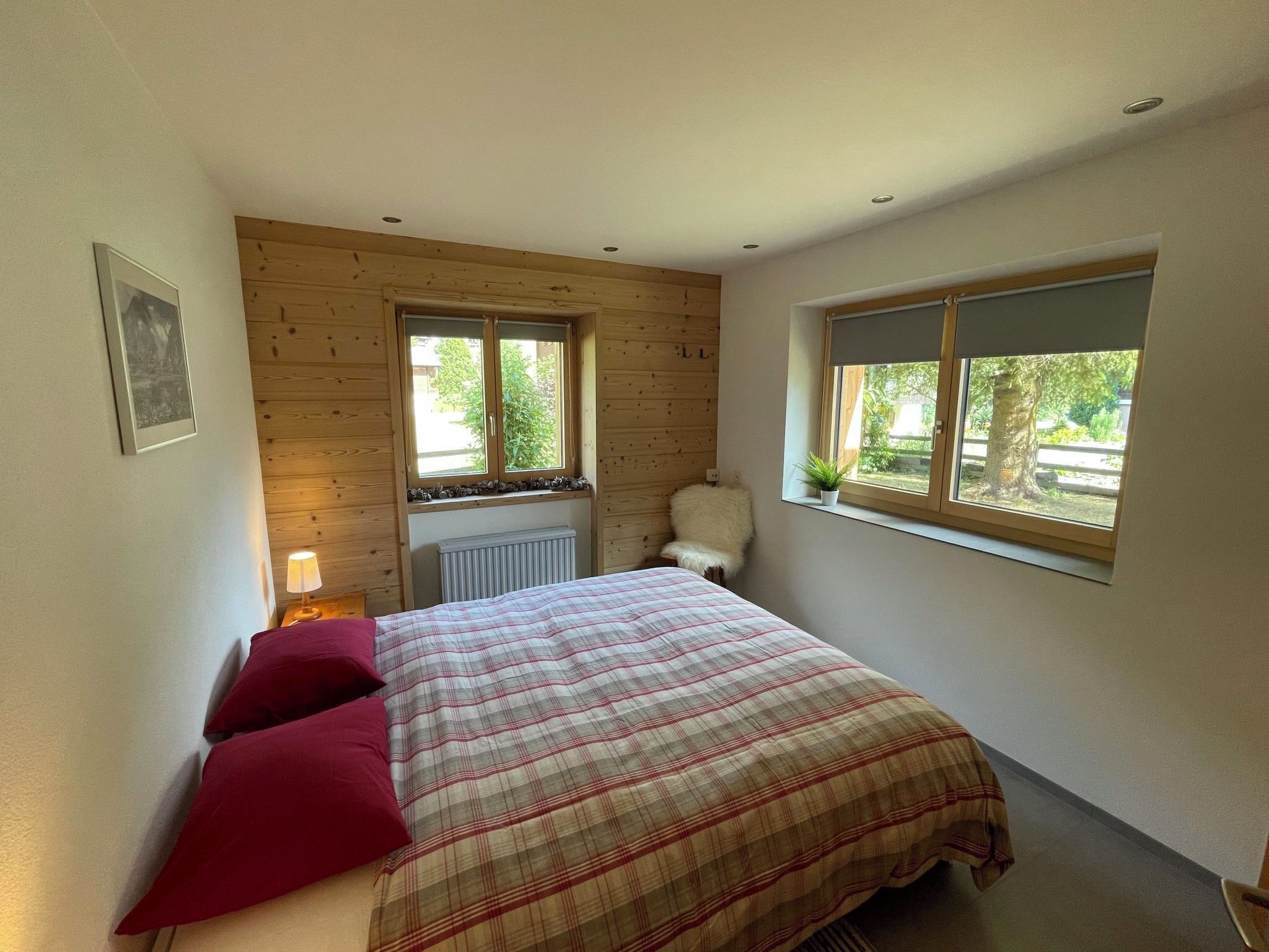 Un dormitorio con cama, ventana, radiador y un cuadro colgado en la pared.
