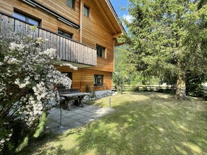 A wooden house with a balcony, a patio with a table and chairs, and a well-maintained lawn. - Ilse EG Süd-West Appartement/Fewo, Dusche oder Bad, WC 3 Zimmerwohnung, 3-Betten by Interhome (Fiesch)