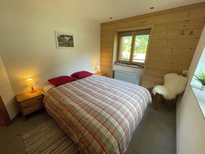 A bedroom with a bed, two bedside lamps, a window, a radiator, a chair, and a wall-mounted picture. - Ilse EG Süd-West Appartement/Fewo, Dusche oder Bad, WC 3 Zimmerwohnung, 3-Betten by Interhome (Fiesch)