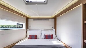 Ein schmales Zimmer mit einem Bett, einem Oberlicht und einem Fenster mit Blick auf Grünfläche.