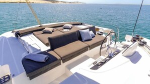 Das Deck einer Yacht mit einer Couch, Kissen und einem kleinen Tisch.