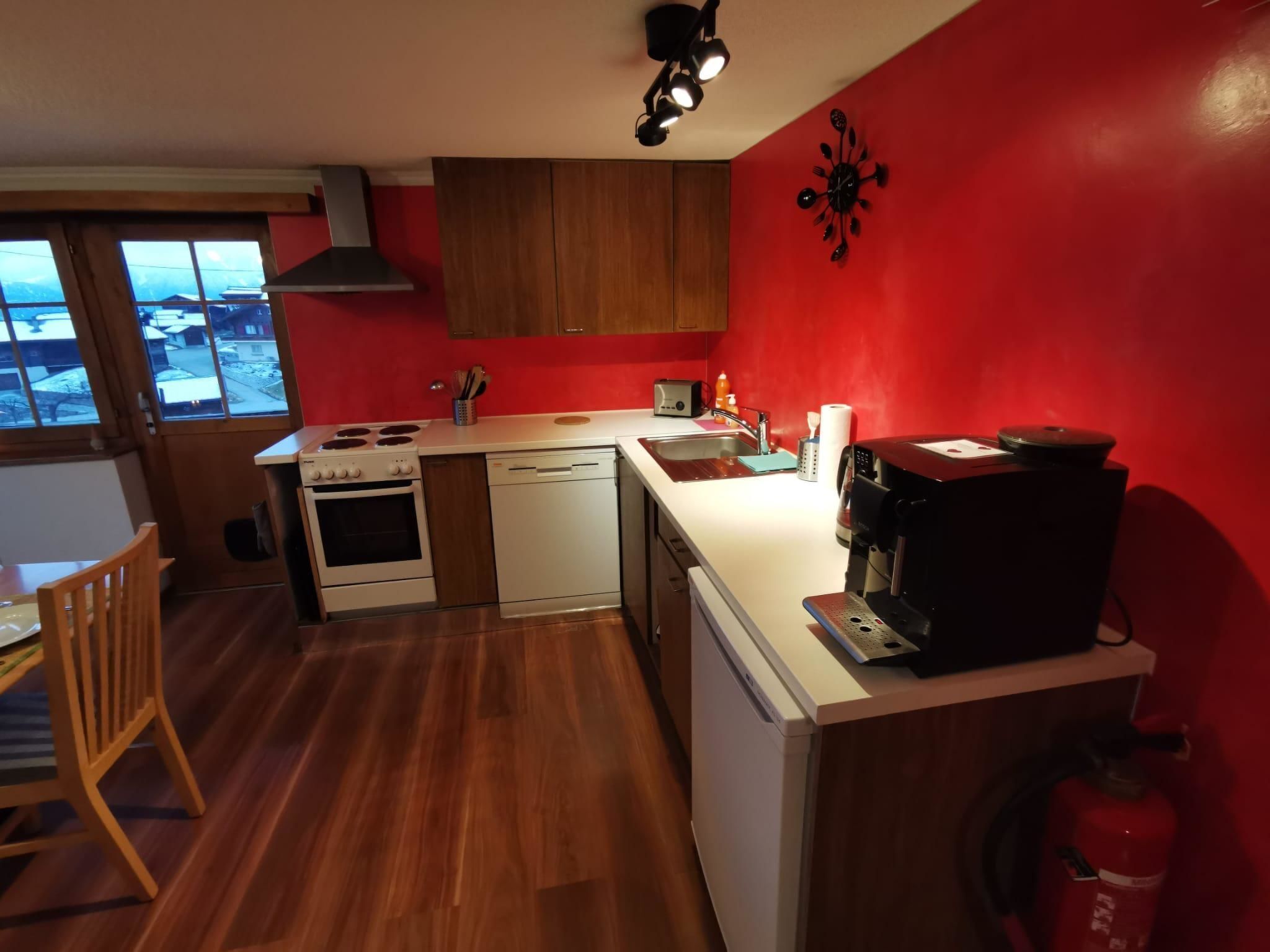 A compact kitchen with a stove, oven, dishwasher, and a coffee maker on the counter.