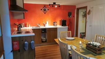 Una cocina compacta con una isla central, un comedor con sillas de madera y una pared de acento roja.