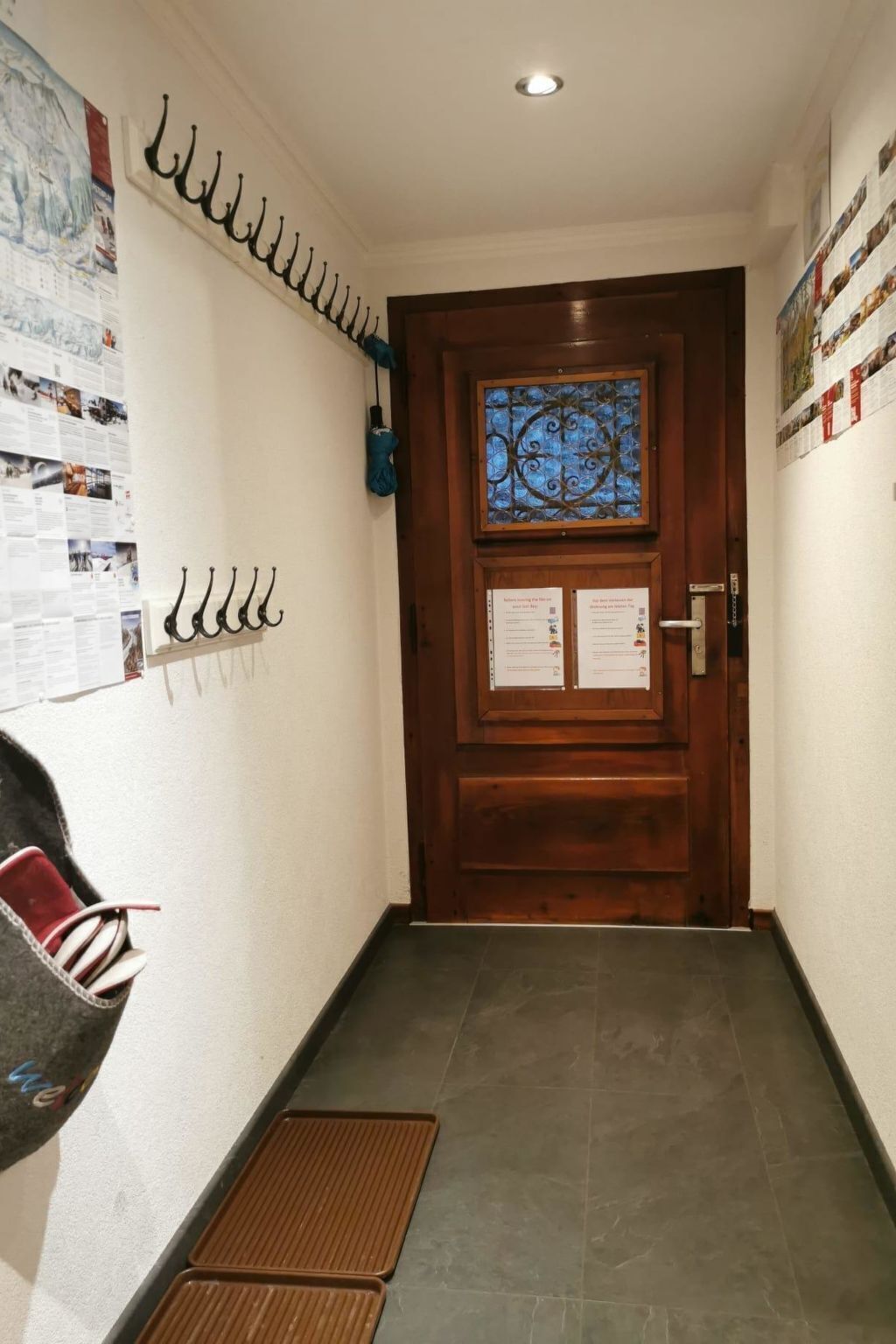 Um corredor com uma porta de madeira, um mural de avisos e um cabideiro.