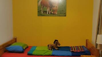 Een kleine kamer met een enkel bed, een houten hoofdbord, een nachtkastje en een lamp.