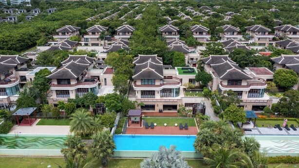 Un barrio residencial con casas de estilo tradicional, piscina y abundante vegetación.