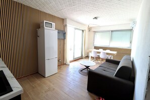 Un espace de vie compact comprenant un coin cuisine, un coin repas et un coin salon.