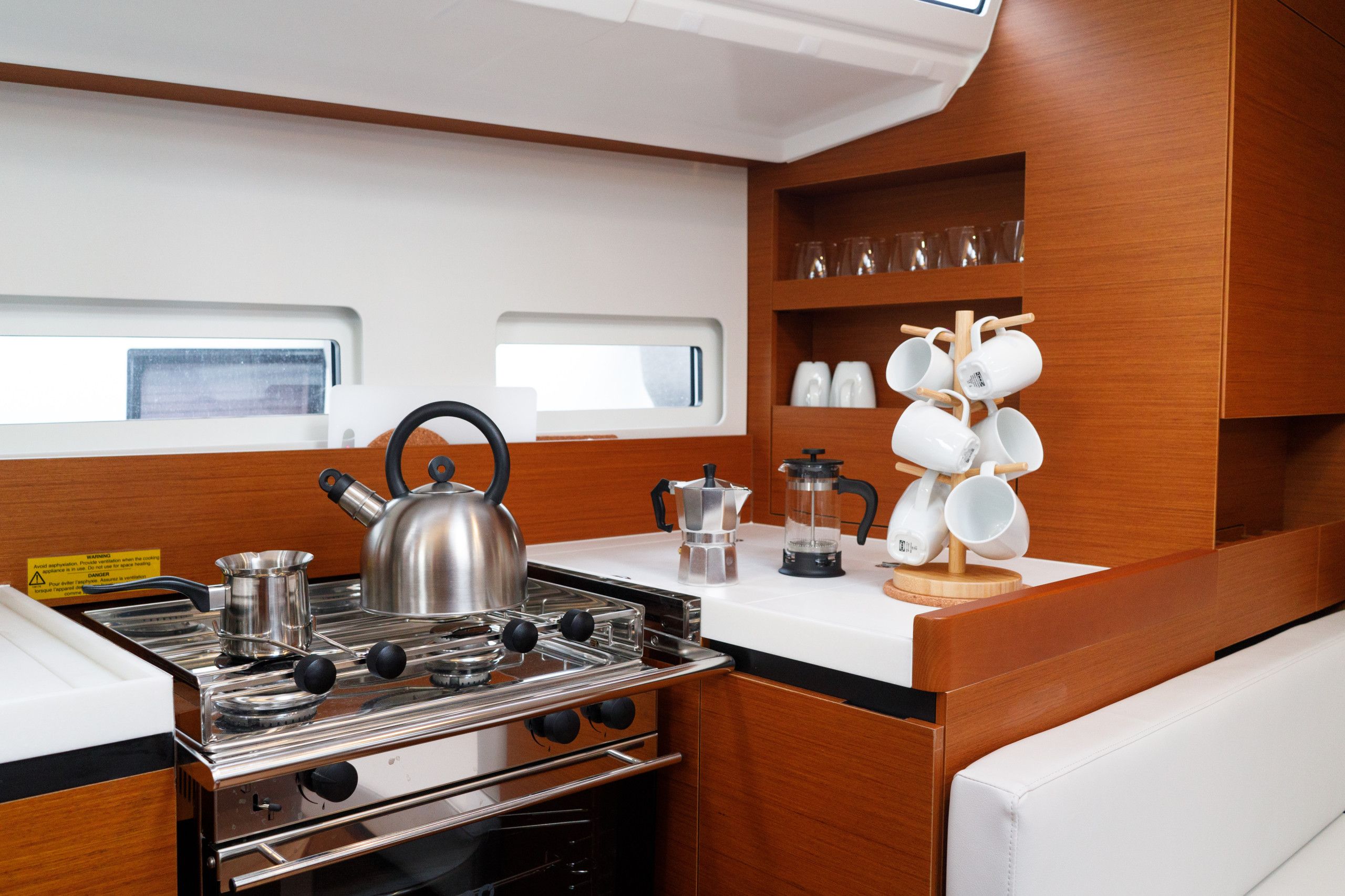 Cocina compacta con estufa, hervidor y cafetera, además de un escurreplatos de pared.
