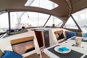 A boat's interior with a dining area, cushioned seating, and a view of the water. - Sun-Kissed Sailing Adventure in the Ionian Islands, Lefkada (Lefkada)