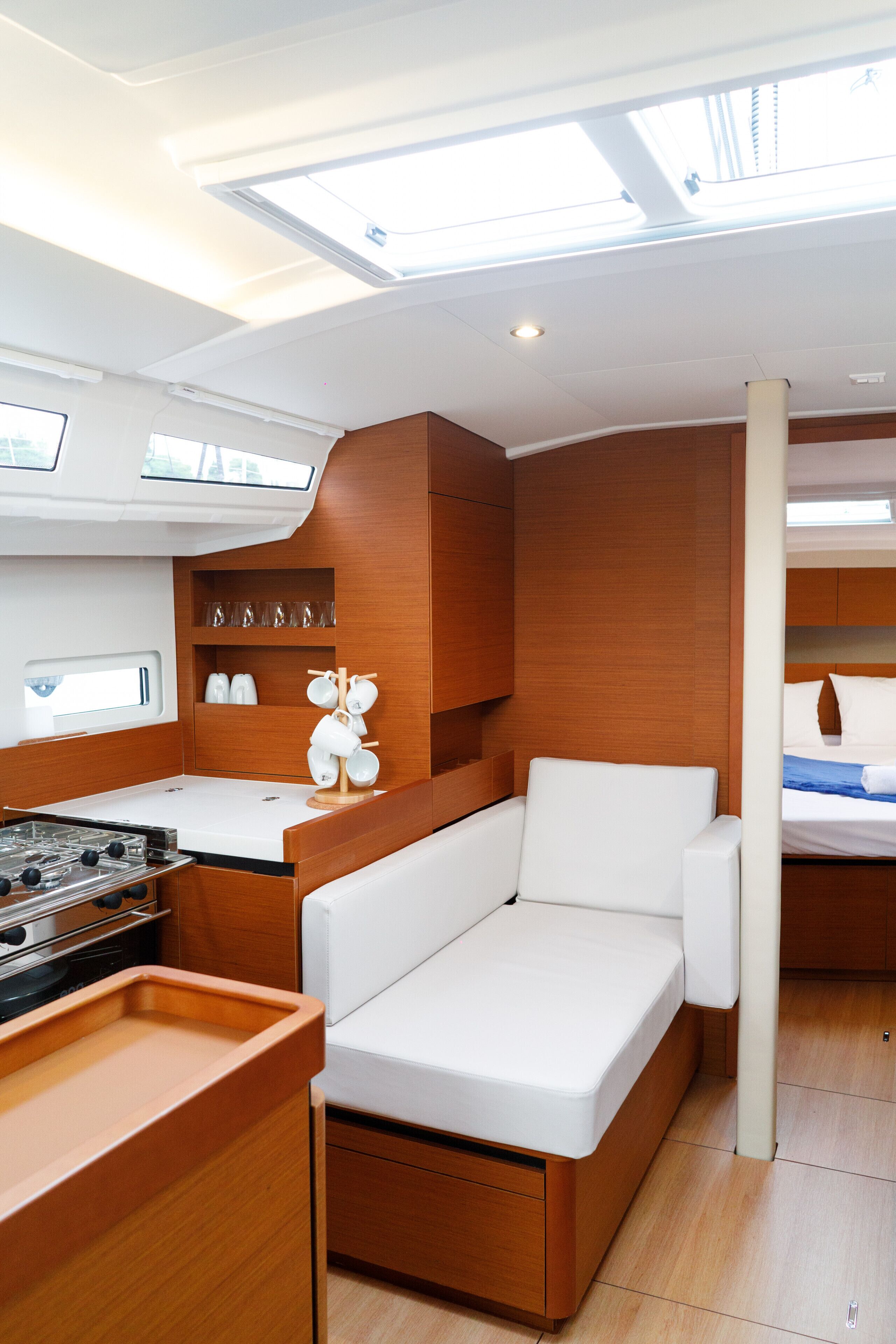 Interior de barco compacto con kitchenette, zona de estar y cama.