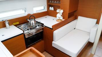 Cocina compacta con estufa, hervidor y encimera blanca.