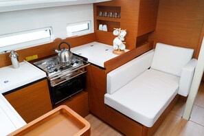 Une cuisine compacte équipée d’une cuisinière, d’une bouilloire et d’un plan de travail blanc.