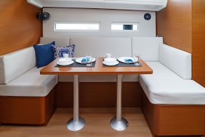 Un coin repas compact comprenant une table, des sièges rembourrés de couleur blanche et une petite fenêtre.
