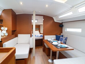 A compact interior with a dining area, a small bed, and a seating area. - Sun-Kissed Sailing Adventure in the Ionian Islands, Lefkada (Lefkada)