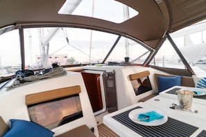 A yacht's interior with a dining area, a small galley, and a seating arrangement.