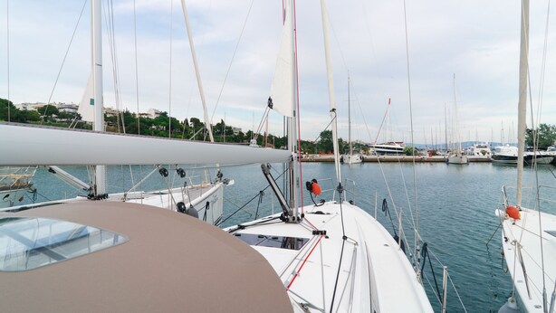Ein Yachthafen mit mehreren angedockten Segelbooten, blauem Himmel und Gebäuden im Hintergrund.