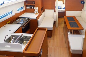 A compact galley with a stove, sink, and seating area. - Sun-Kissed Sailing Adventure in the Ionian Islands, Lefkada (Lefkada)