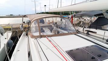 Un velero amarrado en un puerto deportivo con una cabina cubierta y diverso equipo náutico.