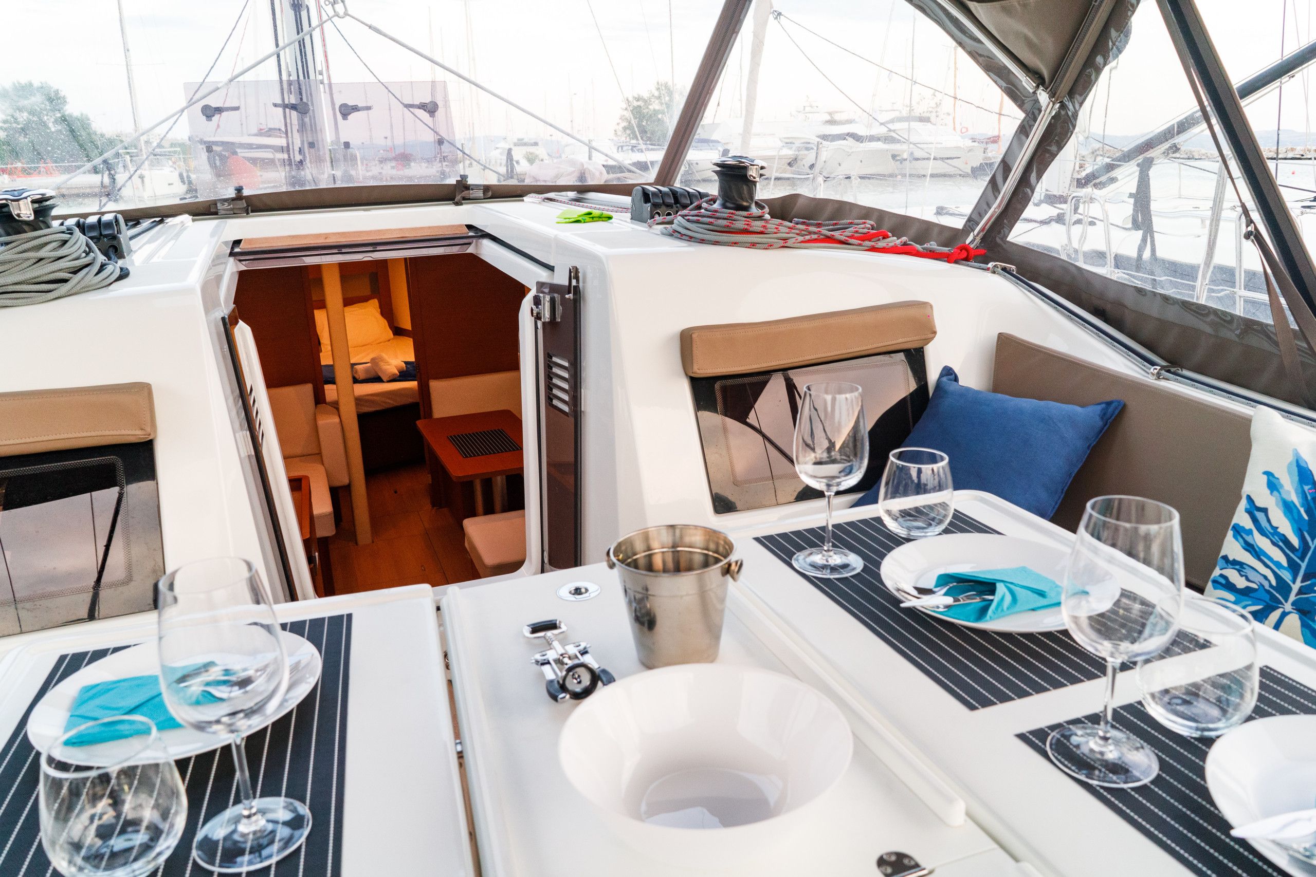 A boat's interior with a dining area, a small seating area, and a view of the marina.