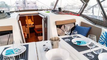 A boat's interior with a dining area, a small seating area, and a view of the marina.