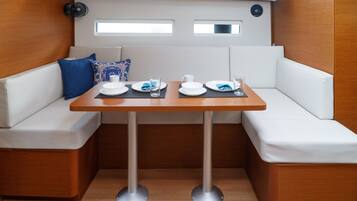 Un comedor pequeño con una mesa, asientos acolchados blancos y un ventilador.