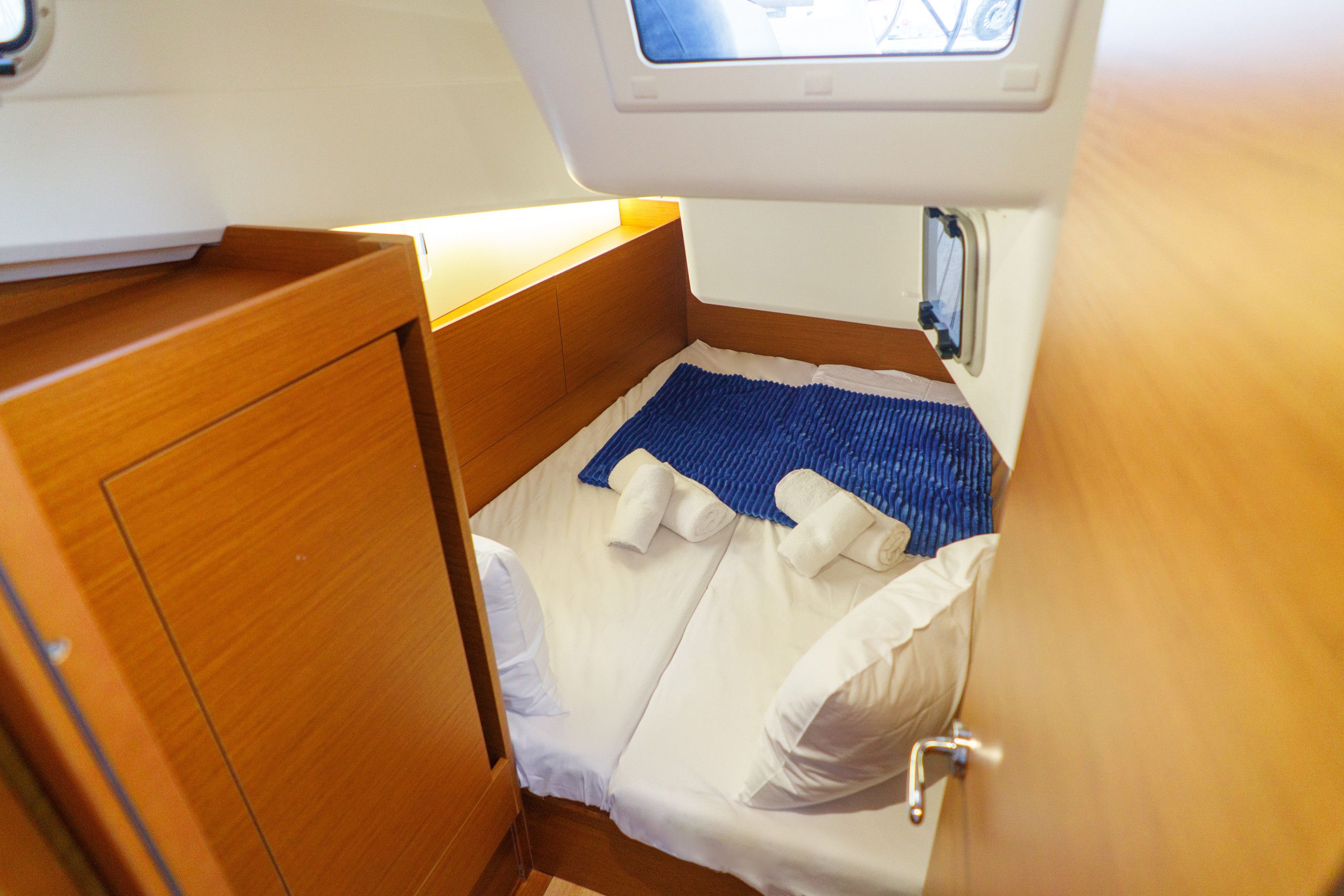 Una zona compacta para dormir con cama, almohadas y un tapete azul.
