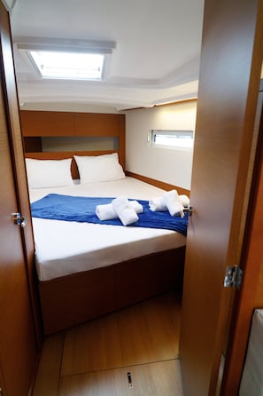 A compact, well-lit bedroom with a single bed, a window, and a door.
