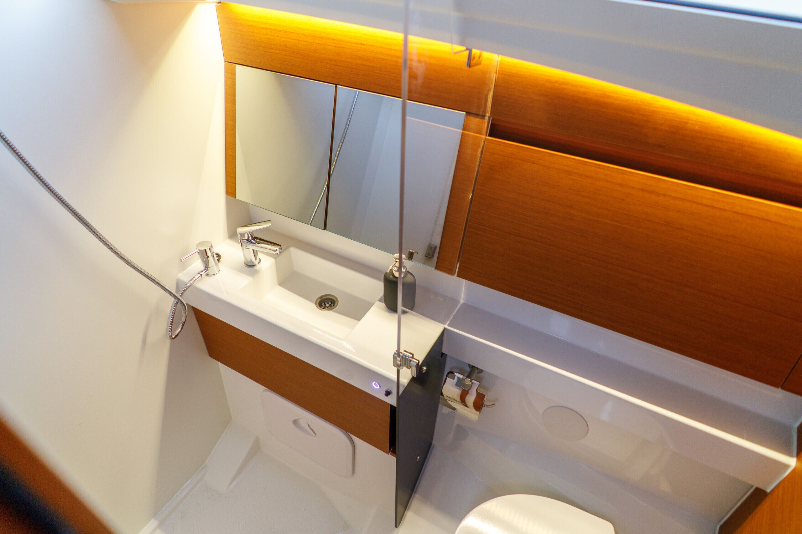 Un baño con lavamanos blanco, espejo y tocador de madera.