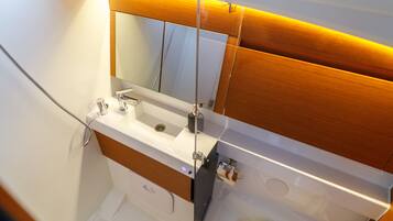 Un baño con lavamanos blanco, espejo y tocador de madera.