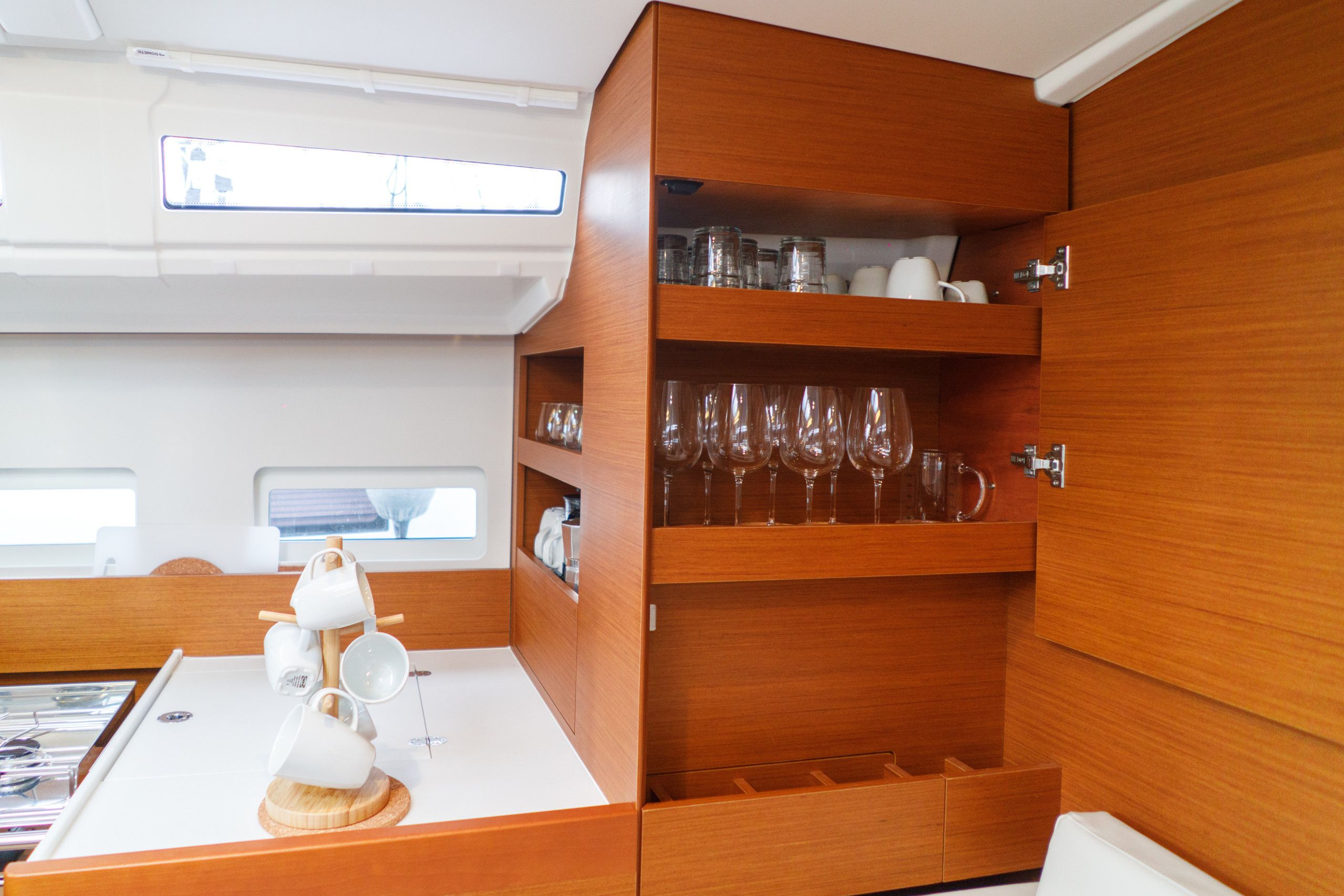 A compact kitchen area with wooden cabinetry, a white countertop, and a window above the sink.