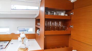 A compact kitchen area with wooden cabinetry, a white countertop, and a window above the sink.
