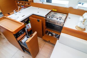 A compact kitchenette with a stove, sink, and storage drawers.