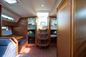 A narrow corridor with bunk beds, a skylight, and a small table with a chair.