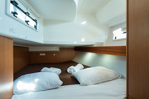 Une cabine compacte équipée d’un lit superposé, d’une petite fenêtre et d’un panneau de commande situé au-dessus du lit.