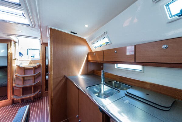 A compact kitchen with a sink, wooden cabinets, and a window.