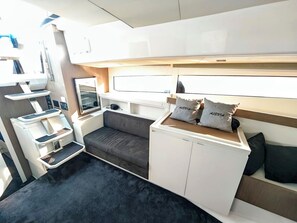 A compact interior with a sofa, a small table, a cabinet, and a window. - Sun-Kissed Sailing Adventure in Zadar, Croatia (Bibinje)