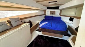 Un interno compatto e moderno con un letto, mobili contenitori e una finestra che garantisce luce naturale.