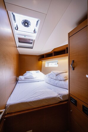 A compact cabin with a bed, a small window, and a ceiling fan. - Sun-Kissed Sailing Adventure in Split, Croatia (Kaštel Gomilica)