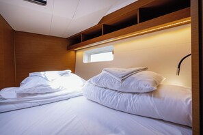 Ein Schlafzimmer mit zwei Betten, hölzernen Kopfteilen, einem kleinen Fenster und eingebauten Regalen.