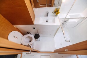 A compact bathroom with a toilet, sink, and shower. - Sun-Kissed Sailing Adventure in the Ionian Islands (Nikiana)