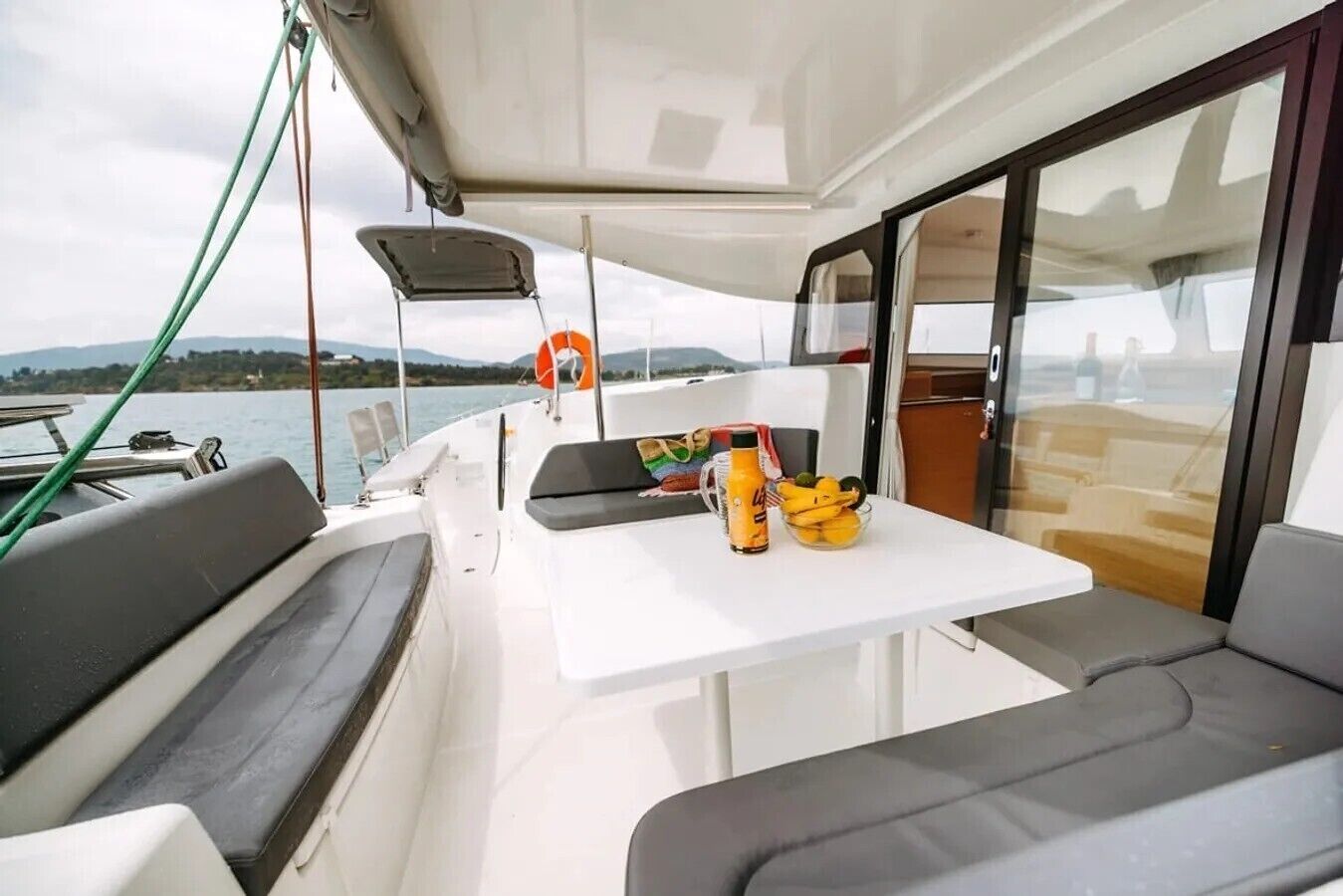Schiffes Inneres mit Tisch, Sitzgelegenheiten und Blick auf das Wasser.