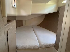 A compact, well-lit interior with a single bed, a small cabinet, and a ceiling-mounted light fixture.