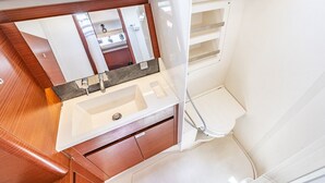A compact bathroom with a white sink, mirror, and toilet. - Sun-Kissed Sailing Adventure in the Ionian Islands, Lefkada (Lefkada)