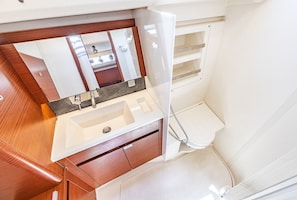 A compact bathroom with a white sink, mirror, and toilet. - Sun-Kissed Sailing Adventure in the Ionian Islands, Lefkada (Lefkada)