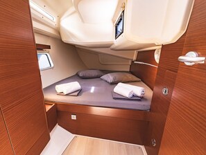 Ein kompakter, gut beleuchteter Innenraum mit Bett, Kissen und einem kleinen Fenster.