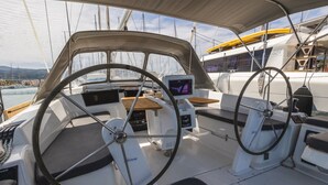 Het dek van een boot, met een stuurwiel, bedieningspaneel en zithoek.