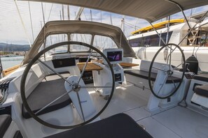 Le pont d’un bateau, avec un volant, un panneau de commande et un espace pour s’asseoir.